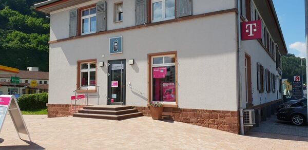 Telekom Shop in einem hellen Gebäude mit Werbeschildern und Zugang über Treppenstufen.