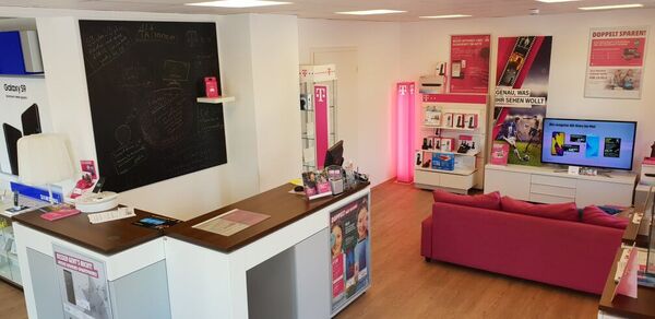 Telekommunikationsladen mit Beratungstheke, Produkten, Werbepostern und gemütlicher Sitzecke.