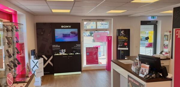 Moderner Telekom-Shop mit Smartphones, Sony-Display, Beratungstheke und Werbeplakaten.